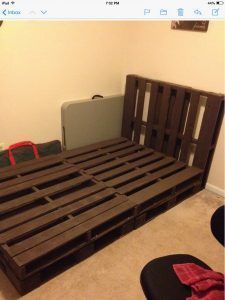 a bed frame made out of wooden pallets in a room with carpeted flooring