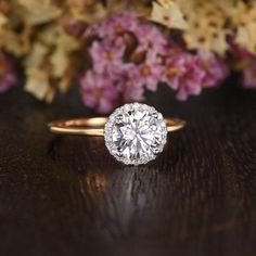 a diamond ring sitting on top of a wooden table next to some purple and white flowers