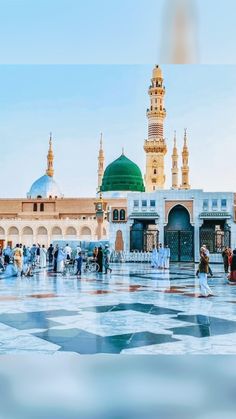 many people are standing around in front of a large building with green domes and minas