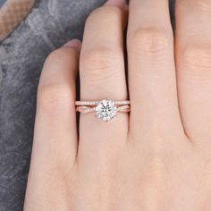 a woman's hand with a diamond engagement ring on her left hand, and the other hand holding an engagement ring