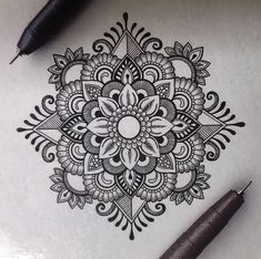 a drawing of a flower on paper next to a pen