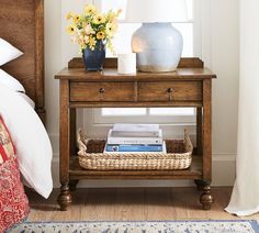 a wooden table with a basket on top of it next to a bed and window