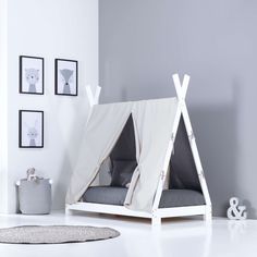 a teepee tent bed with pillows and blankets on the floor in front of a gray wall