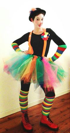 a woman dressed in colorful clothing standing on a hard wood floor with her hands on her hips