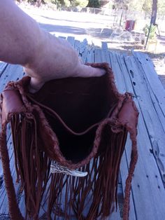 This boho fringed leather tote handbag is made is soft mahogany cowhide leather. It has fringe all around and measures 10 inches tall x 10 inches wide x 2.75 inches deep. There is an extra pocket inside. The beaded turtle totem is done mostly in shades of green glass seed beads and has a center focal of eagle feathers. There are also four directional colors inside the turtle totem. (Refer to the picture.) If you would like a different beaded rosette contact us. The beaded rosette is sewn on and Artisan Shoulder Bag With Tassels For Everyday, Fringe Bucket Bag Tote For Travel, Brown Hobo Bag For Festival, Brown Bucket Bag For Festival, Handmade Brown Bucket Bag For Festivals, Brown Bucket Shoulder Bag For Festival, Leather Hobo Bag Tote For Festival, Bohemian Bags With Beaded Fringe For Everyday Use, Traditional Fringe Shoulder Bag For Everyday Use