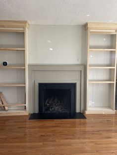 an empty living room with wood floors and white walls, including a fireplace in the center