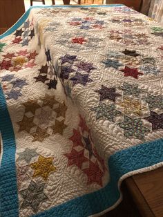 a quilted table topper with stars on it sitting on a wooden chair next to a window