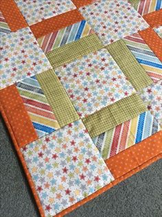 an orange and white quilted table topper on the floor in front of a gray carpet