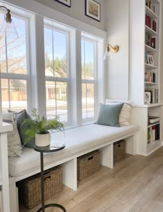 a white window seat with two windows and some bookshelves in the back ground