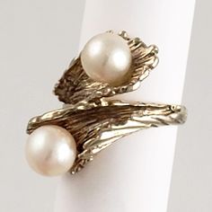 "This 18K yellow gold ring has a distinctive bypass design with two beautiful pearls. The naturalistic ring conveys the feel of coral or foliage, with a textured surface that hugs the pearls. This vintage statement ring will graze the knuckle on most women. Vintage: 1970s Size: 5 1/4 Materials: 18K Yellow Gold, Cultured Pearls Marked: 18K 2 Cultured Pearls: approx. 7mm Width North to South: 1\" Stands Off Finger: 3/8\" Shank Width: 1/8\" Weight: 5.2 dwt / 8.5 g / .26 ozt Condition: Very Good FRE Unique White Gold Pearl Ring For Formal Occasions, Unique Polished Pearl Ring For Wedding, Unique Wedding Pearl Ring With Polished Finish, Unique Oval Pearl Ring For Anniversary, Unique Yellow Gold Pearl Ring For Anniversary, Naturalistic Design, Bypass Ring, Kiss Makeup, 18k Yellow Gold Ring