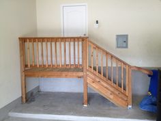 a wooden staircase leading up to a white door in a room with concrete flooring