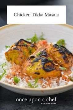 chicken tikka masala served over rice in a white bowl with garnishes