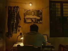 a man sitting at a desk in front of a wall with a poster on it