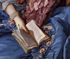 a painting of a woman reading a book on a blue satin bed spread with roses