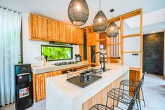 a kitchen with two hanging lights above the sink and an aquarium in the center of the island