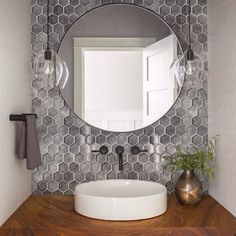 a bathroom vanity with a round mirror above it and a vase on the counter next to it