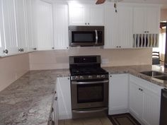 a kitchen with marble counter tops and white cabinets