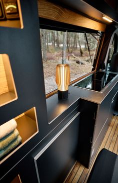 the interior of an rv with wood flooring and black walls, including a lamp