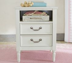 a white nightstand with two drawers on top of pink carpeted floor next to window