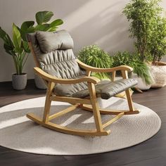 a wooden rocking chair sitting on top of a rug next to a potted plant