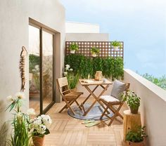 a balcony with potted plants and chairs on the floor next to an open door