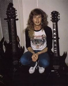 a man sitting on the floor next to two guitar heads in front of his face