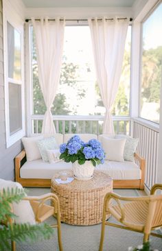 a white couch sitting on top of a wooden floor next to a table with blue flowers