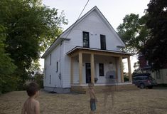 a young boy standing in front of a white house