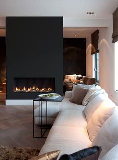 a living room with a large white couch and fire place in the wall behind it