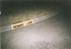 there is a sign that says memory lane on the side of the road in front of an empty street