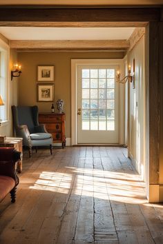 the sun shines in through two windows onto a wood floored entryway with an antique chair