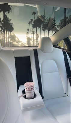 a cup of ice cream sitting on the back seat of a car with palm trees in the background