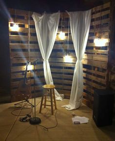 an empty room with some lights on the wall and curtains hanging from the ceiling in front of it