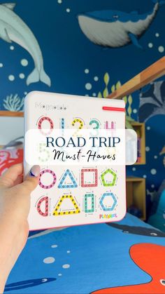 a person holding up a book with the words road trip must haves written on it