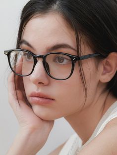 a woman wearing glasses with her hand on her head and looking off to the side