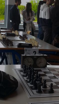 several people standing around a table with chess pieces on it