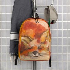 a backpack hanging on a rack in front of a tiled wall with an orange fox design