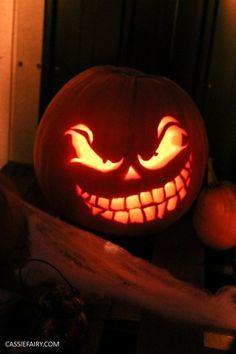 a carved pumpkin sitting on top of a wooden table next to two orange pumpkins