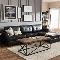 a living room with black leather couches and pictures on the wall above it's coffee table