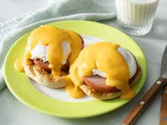 two eggs benedicts with hollandaise sauce on a plate next to a glass of milk