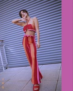 a woman in red and orange striped pants posing for the camera with her hand on her hip