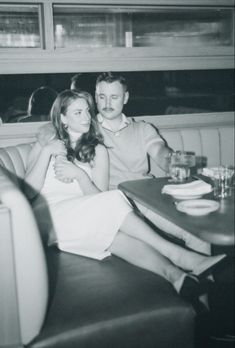 a man and woman sitting next to each other at a table in front of a window