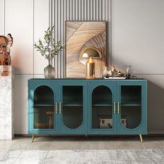 a blue cabinet sitting in front of a white wall next to a vase with flowers