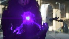 a woman is holding her hands in front of her face with blue light coming from the center