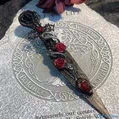 a knife with red roses on it sitting on a stone