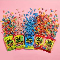 four bags of sour kraut candy on a pink background with sprinkles