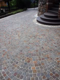 an outdoor walkway made out of cobblestones and stone with stairs in the background