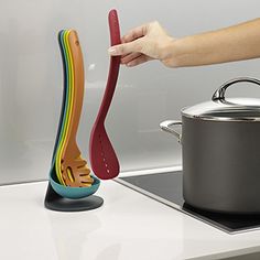 a person is holding a spatula and spoon in front of a pot on the stove