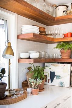 the shelves in this kitchen are filled with plates and bowls, plants, and other things