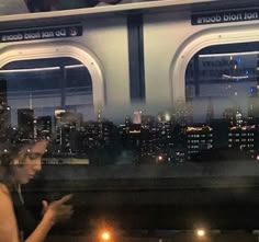 a woman is looking at her cell phone while sitting on a train in the city